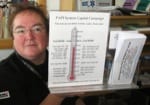 Nancy McPherson, Chef/owner of Nancy’s Airfield Café, holds the PAPI Capital Campaign thermometer.