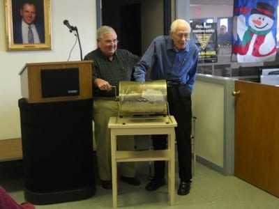 WinnAero Director Don Morrissey, left, assists retired Air Force Col. Robert Fortnam as he picks the winner of the organization’s airplane raffle. The winner of the Cessna 172G, Jane Williams of Florida, was chosen on January 5th at Laconia Municipal Airport in Gilford, NH.